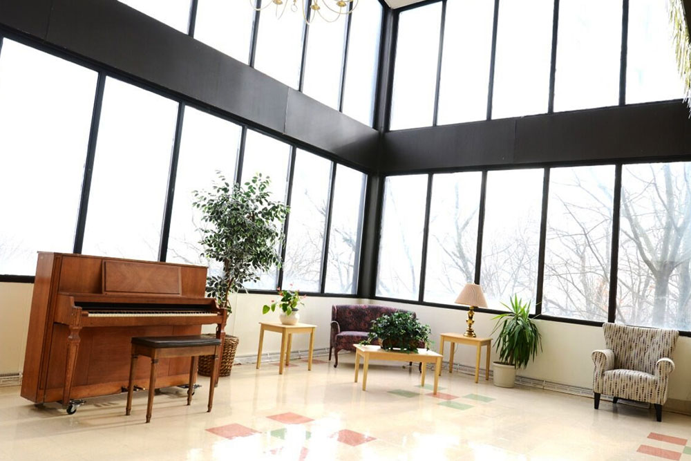 Lobby of Norwalk facility with open concept, tall ceilings, and piano.