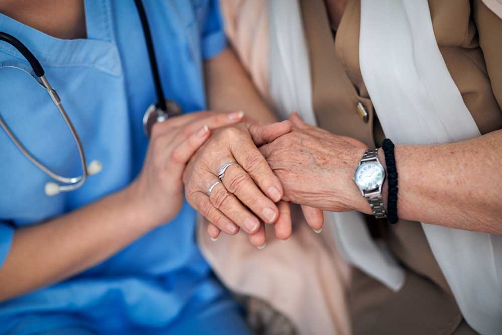 Nurse holding a hands to elderly woman